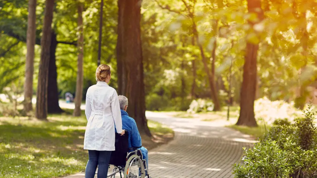 Hospice Services, life at Sequoia Valley, resident in wheelchair being pushed by caregiver on an outdoor walk.