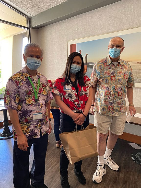 Three Tamalpais team members wearing Hawaiian shirts stand together