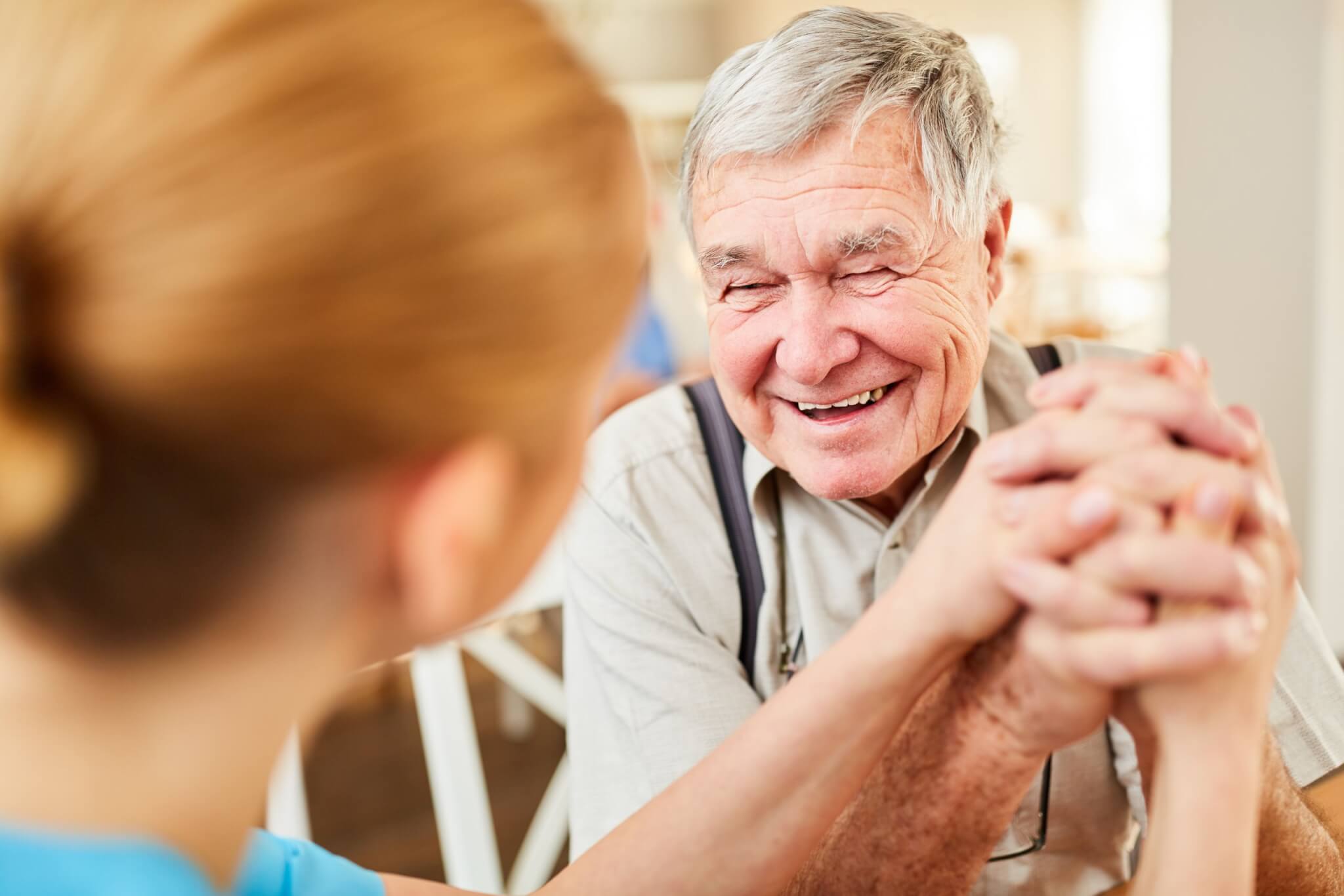 Skilled nursing, older adult male happily holding hands with nurse,