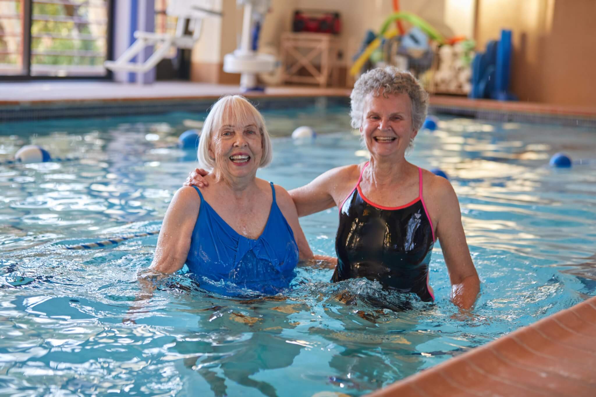 two elderly women swimming in an inside pool