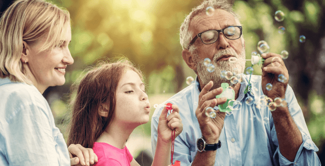 Thanks for Reaching Out. Older man and woman blowing bubbles with child.