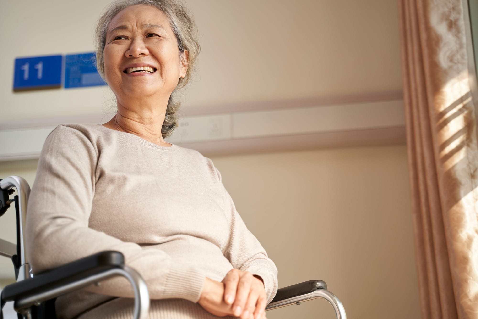 Memory Care. Elderly woman sitting in wheelchair smiling and looking into distance.