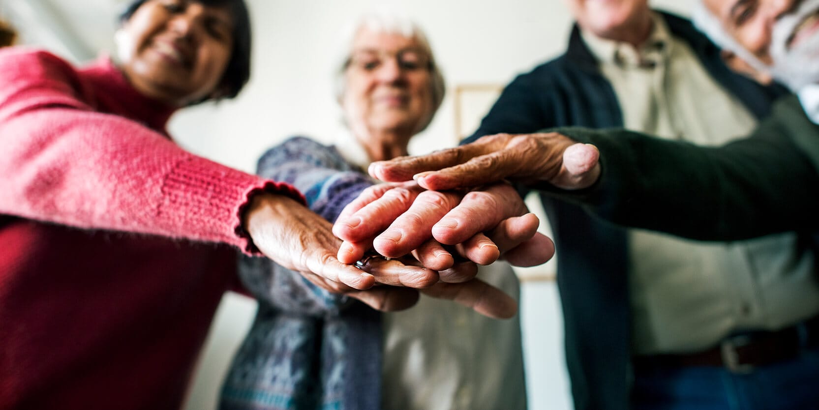 Group of elderly people with their hands together.