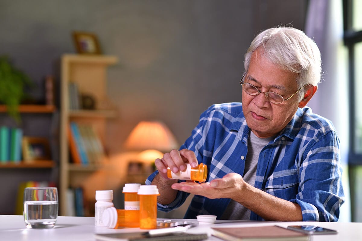 Fall Prevention | Sequoia Living. Elderly man sitting down, pouring medicine from pill bottle.