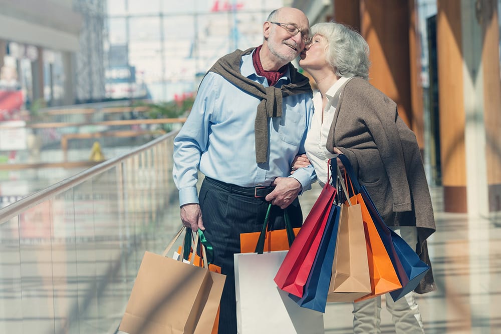 Shopping in Portola Valley Shopping in Portola Valley. Elderly couple carrying shopping bags, kissing at a mall.
