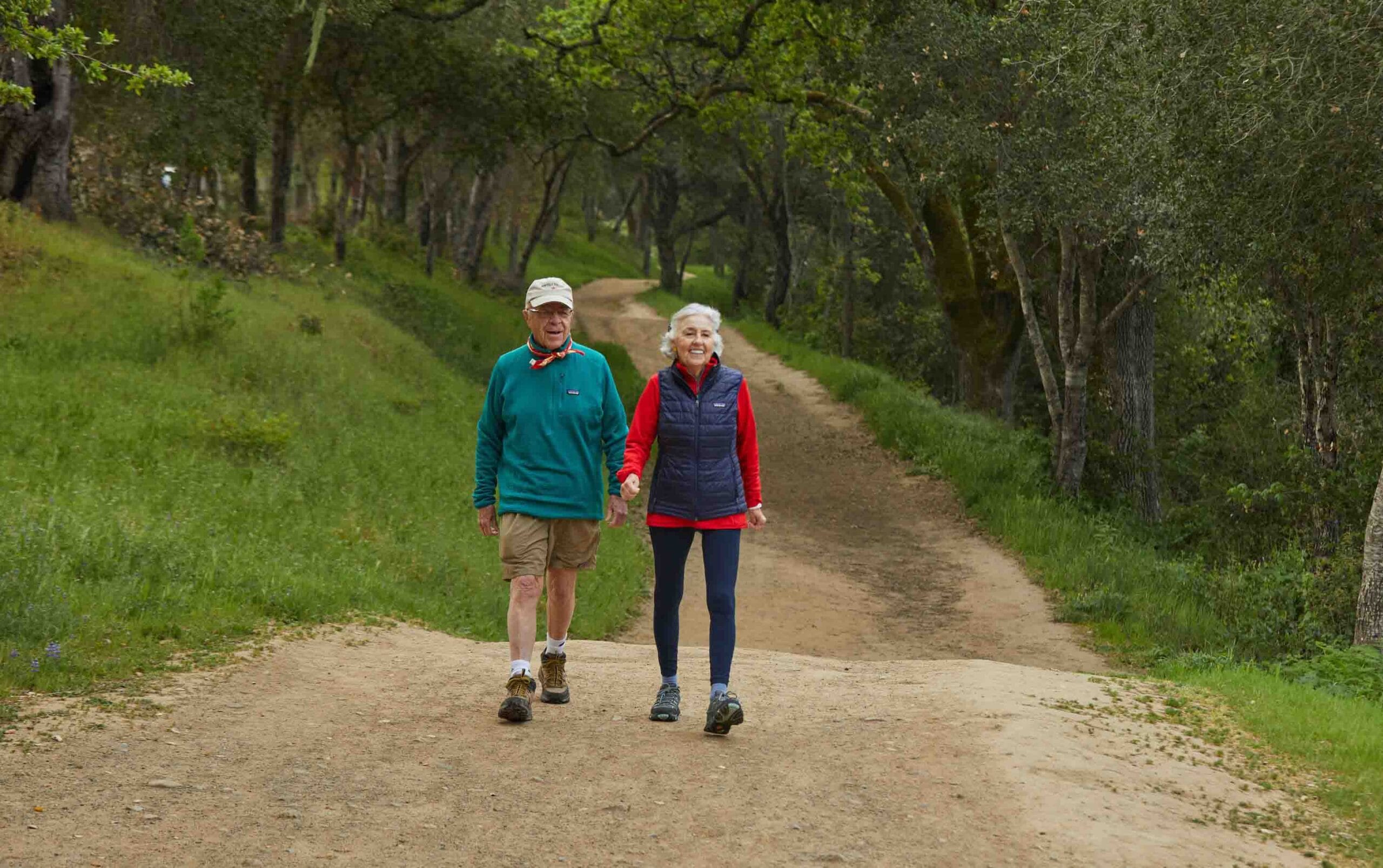 image shows an older couple walking a hiking trail