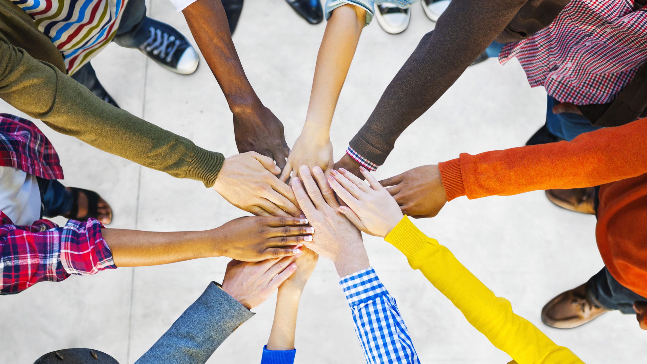 Get Involved at The Sequoias Portola Valley. Group of people standing in circle with hands in the middle.