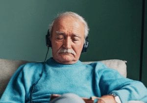 Elderly man sitting down listening to music on a tablet