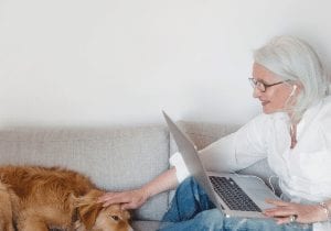 Elderly woman on laptop and petting dog