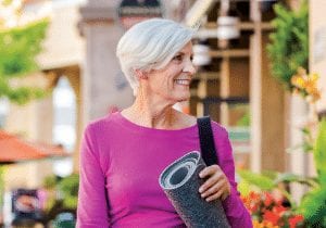 Elderly woman walking while carrying a yoga mat