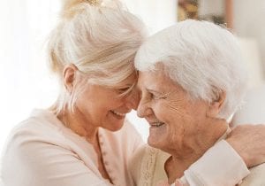 elderly woman being hugged by a woman