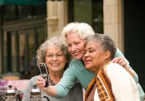 group of elderly women smiling and looking at a phone