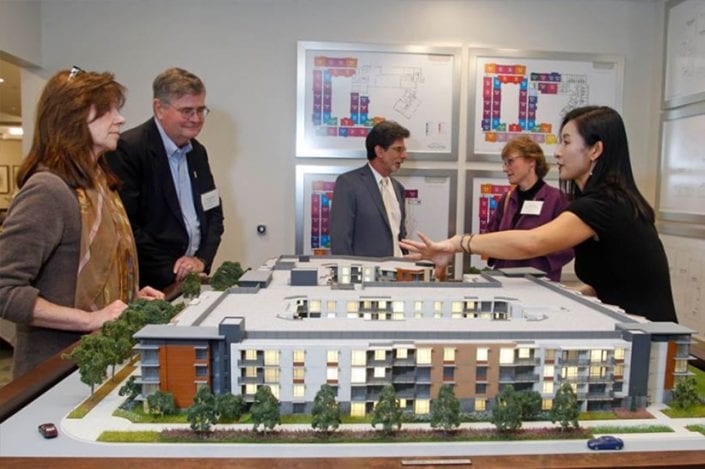 two men and three women examining and talking about model of viamonte at walnut creek building
