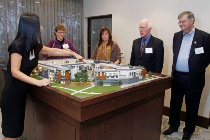 Woman pointing at model of viamonte at walnut creek model building while two men and two women look