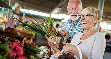 elderly couple picking out vegetables at a market