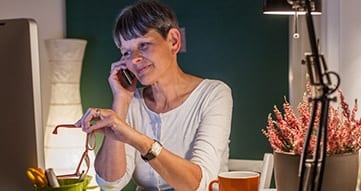 elderly woman sitting at a desk on the phone