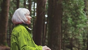 Elderly woman walking in forest