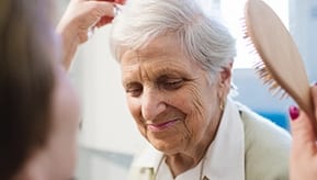 Elderly woman getting her hair brushed