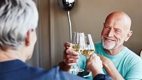 Elderly men toasting wine glasses.