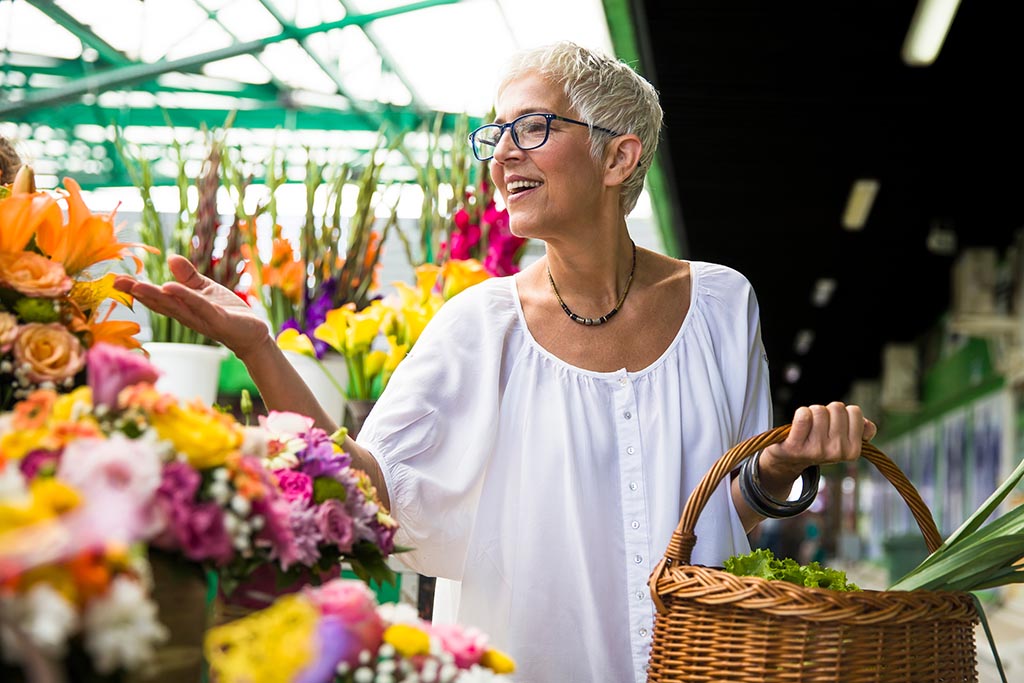 older adult woman buying flowers on local market