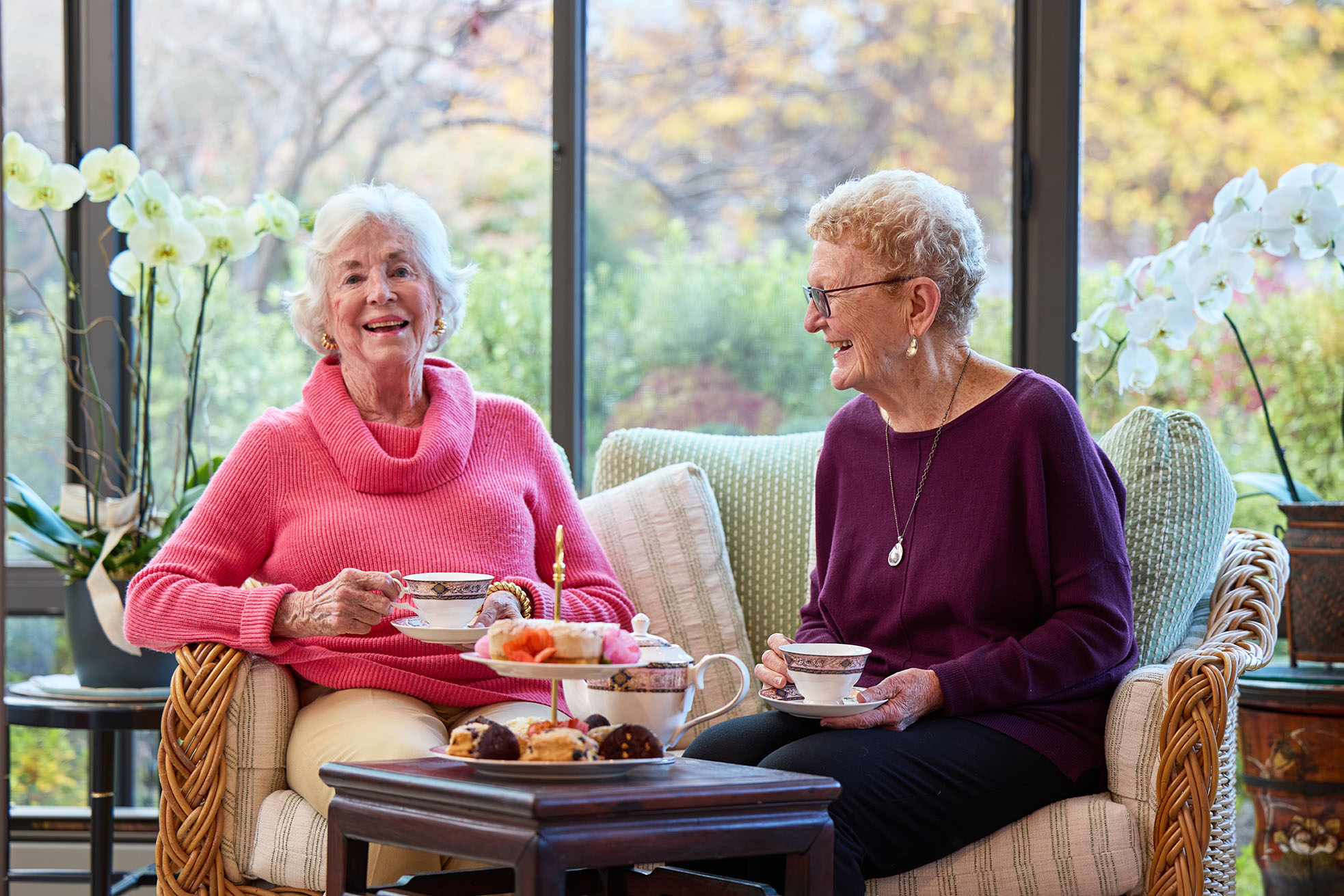 The Sequoias Portola Valley TeaRoom 1863 Two female residents, sitting indoors, with a beautiful natural backdrop, The Sequoias Portola Valley TeaRoom 1863